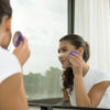 Woman applying cream to her face in front of a mirror