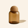 Brown glass bottle with cork stopper on a beige background