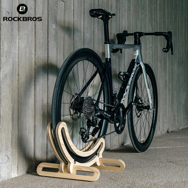 Bicycle on a wooden stand against a wooden wall with 'RockBros' branding.