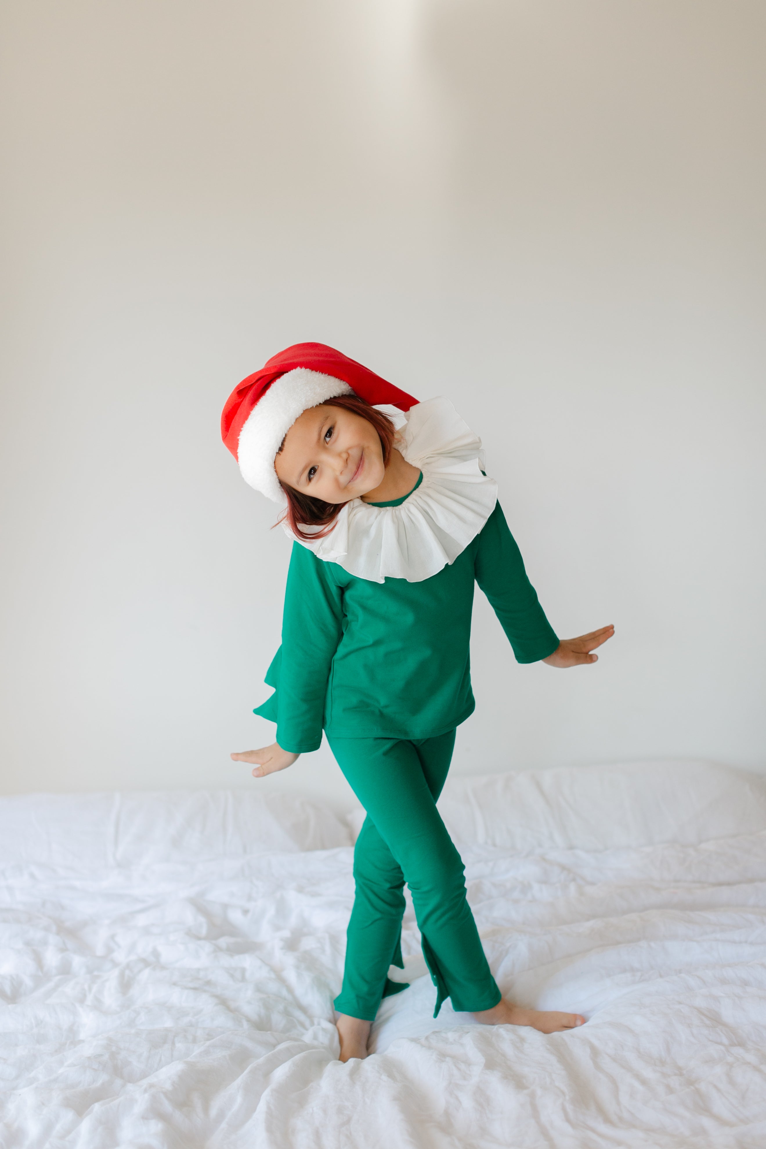 Child wearing an elf costume on a white bed