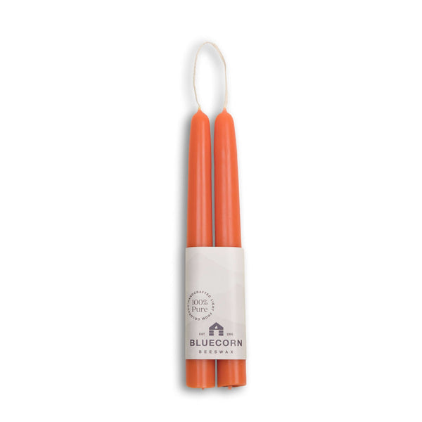 Two orange candles in a cylindrical holder with 'Bluecorn' branding on a white background