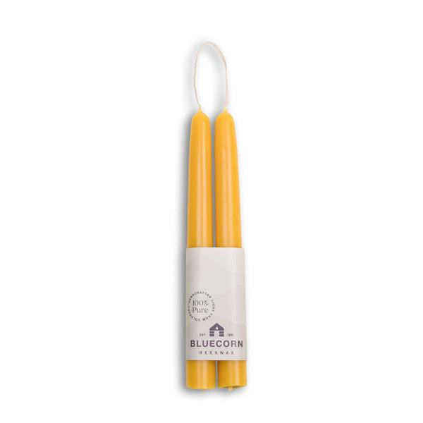 Yellow candles in a white holder with Bluecorn branding on a white background