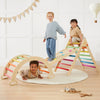 Children playing on a colorful wooden climbing toy indoors.