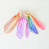 Close-up of Sarah's Silks natural Maple wood teether ring with vibrant silk rainbow attachment