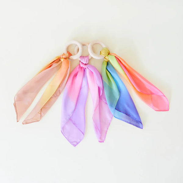 Close-up of Sarah's Silks natural Maple wood teether ring with vibrant silk rainbow attachment