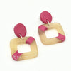 Close-up of Check Box Horn Stud Earrings in light horn and hot pink showing nickel-free ear wires and 2-inch length