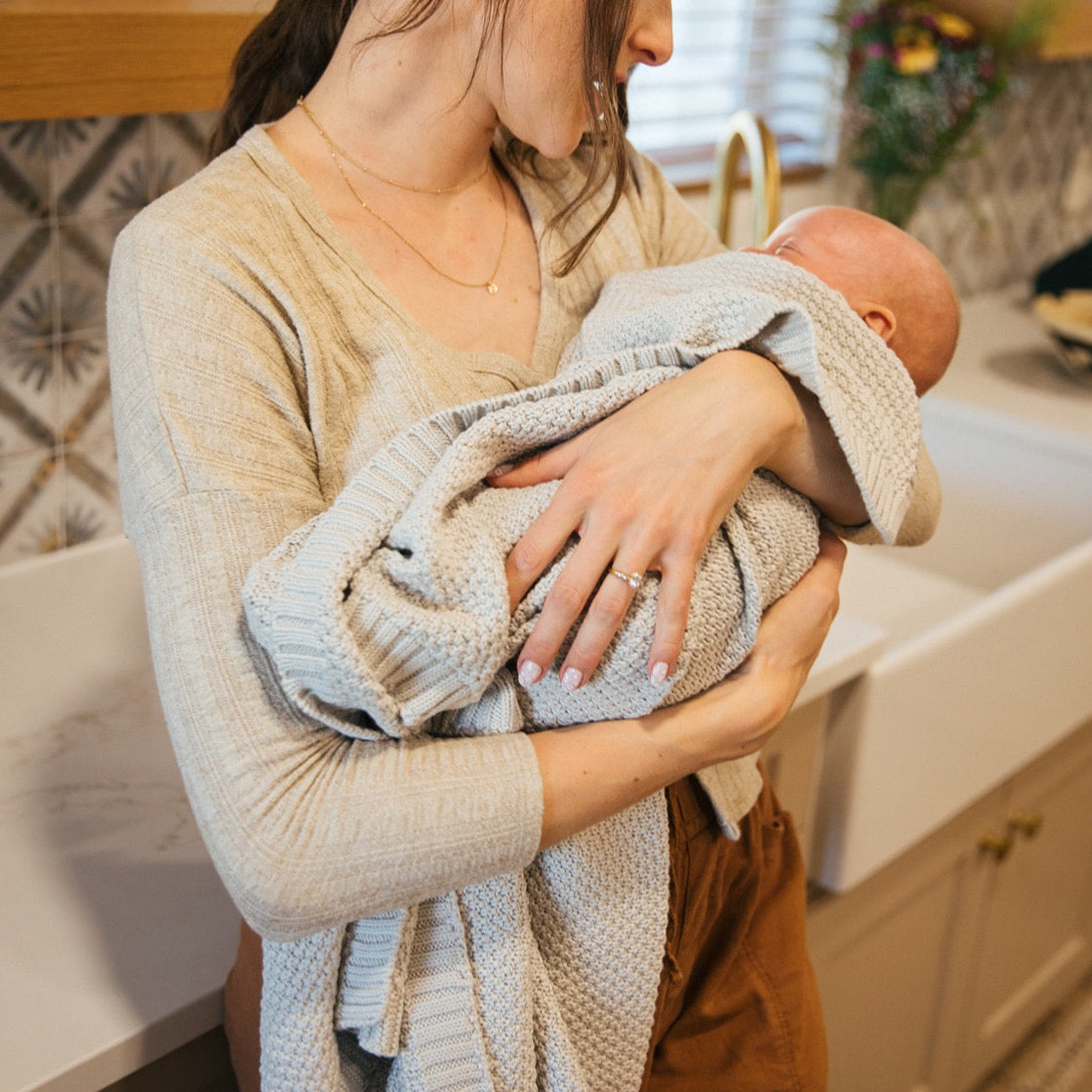 Julep knitted cotton baby blanket by Plum+Sparrow in a soft green hue, folded neatly