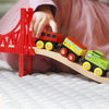 Child playing with a toy train set on a wooden track with a red bridge.