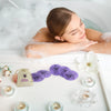 Woman relaxing in a bubble bath with bath bombs and candles.
