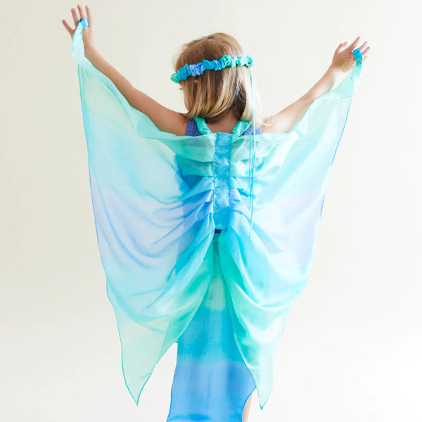 Child wearing a blue fairy costume with wings against a white background