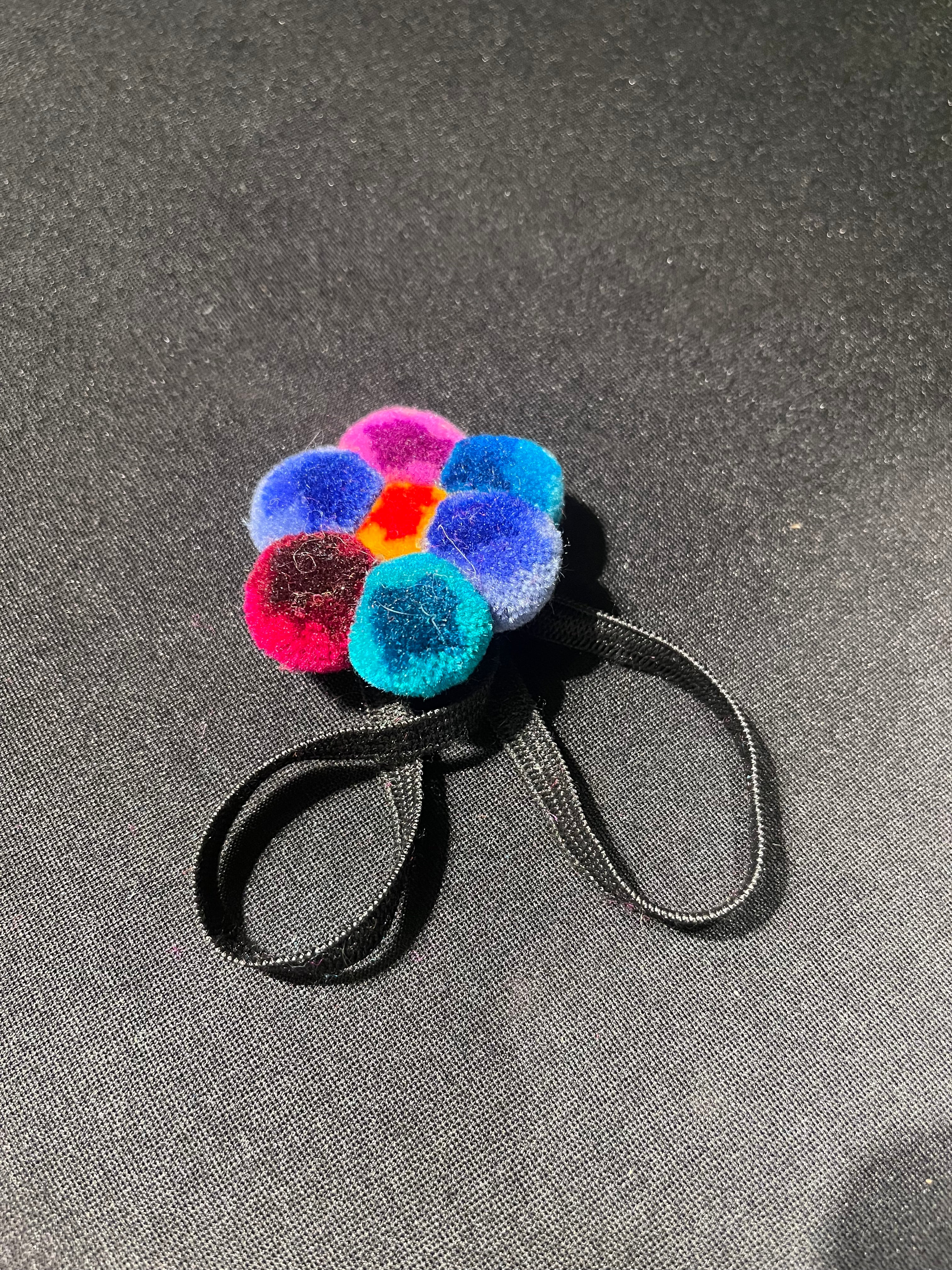 Colorful pom-pom hair tie on a gray background