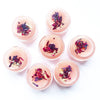 Pink lip balm containers with floral toppings on a white background