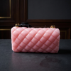 Pink quilted handbag on a dark surface with a dark background