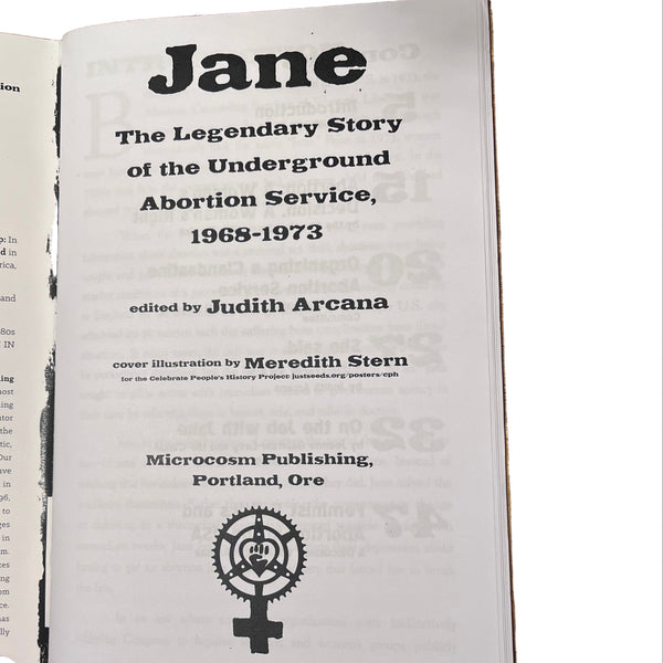 Inside spread of the Jane zine open to body text, showing the story of the Jane Collective, on a wooden surface