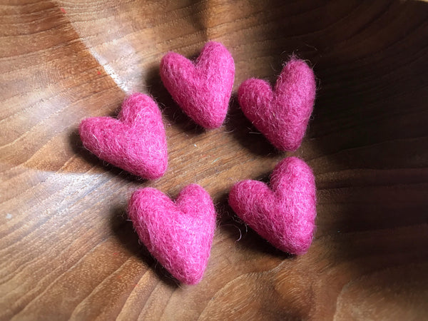 Five small felted wool hearts in Wild Rose Pink, each slightly different in shape
