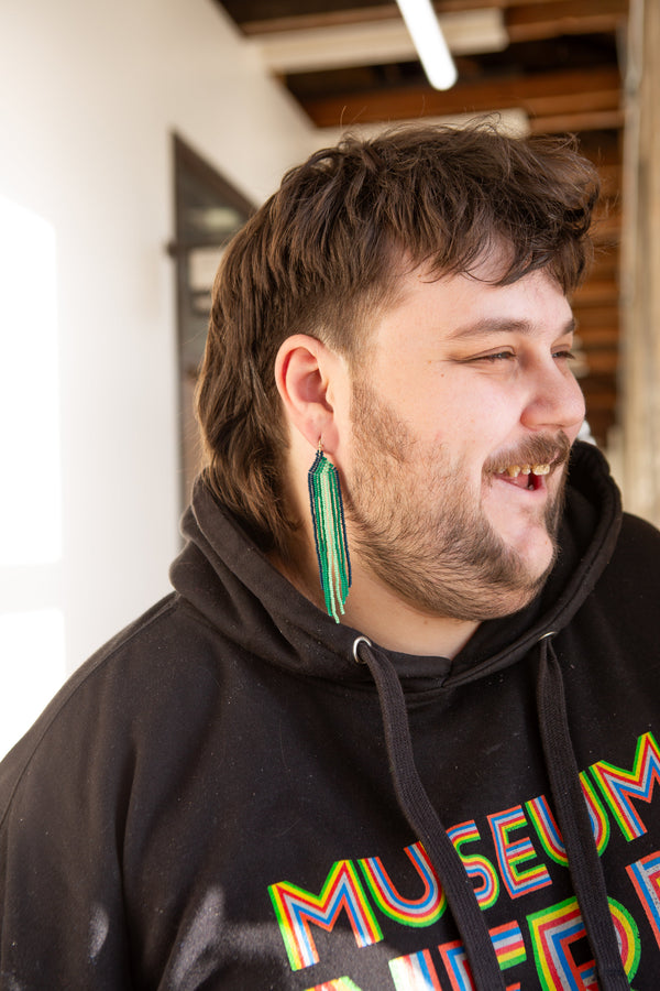 Close-up of vibrant glass bead fringe earrings with gold-toned brass ear wires