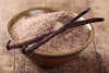 Vanilla sugar in a bowl with vanilla beans on a wooden surface