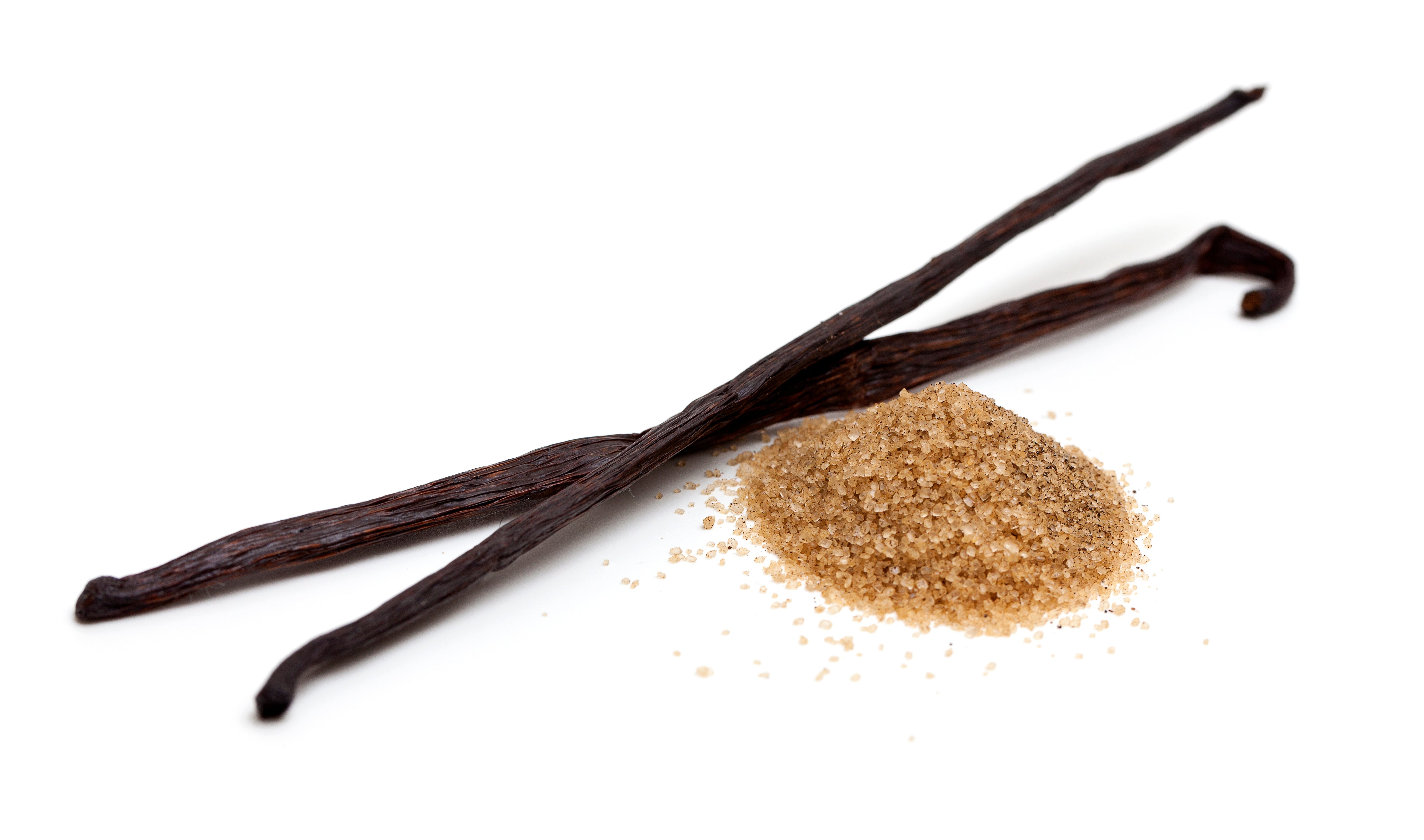 Two vanilla beans and a small pile of brown sugar on a white background