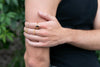 Person wearing multiple gold rings on a blurred green background