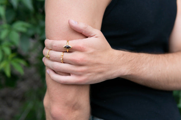 Person wearing multiple gold rings on a blurred green background