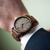 Wooden watch on a person's wrist with a blurred background