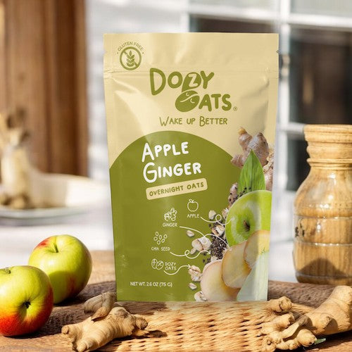 Doyy Oats Apple Ginger Overnight Oats package on a wooden surface with apples and ginger.