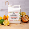 Dishwasher gel container with citrus fruits on a kitchen counter. Sunburst Citrus Automatic Dishwasher Gel — Non-Toxic Plant-Based Dishwasher Detergent | Endocrine Disruptor-Free, PVA-Free & Made in the USA