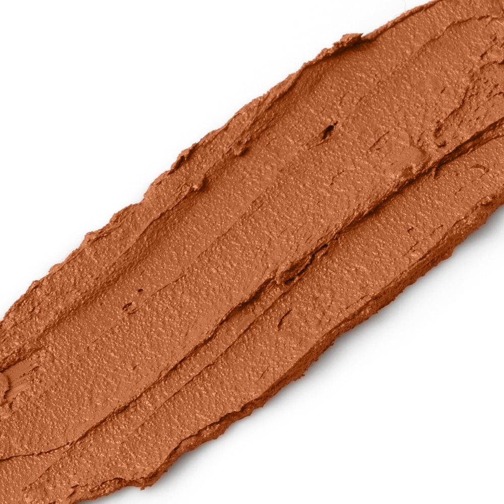 Close-up of a swatch of brown makeup cream on a white background