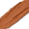 Close-up of a swatch of brown makeup cream on a white background