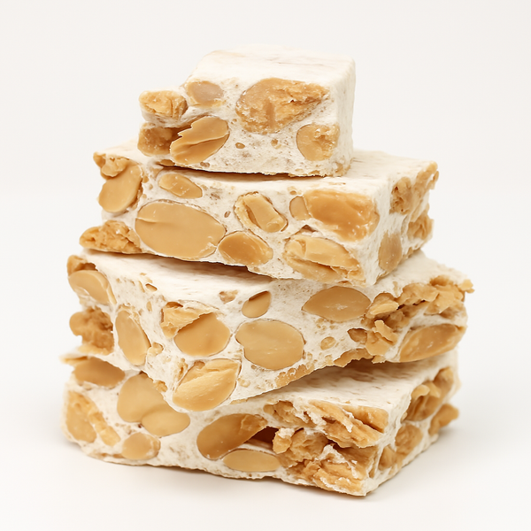 Stack of nougat with almonds on a white background. Indulge in Andy Anand’s Sugar-Free & Gluten-Free Almond Brittle Nougat. Handmade in Spain with roasted almonds and natural sweeteners. Diabetic-friendly, low-carb, and only 2g net carbs per serving. The perfect gourmet gift for health-conscious food lovers!