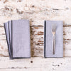 Set of gray napkins with a fork on a rustic wooden surface