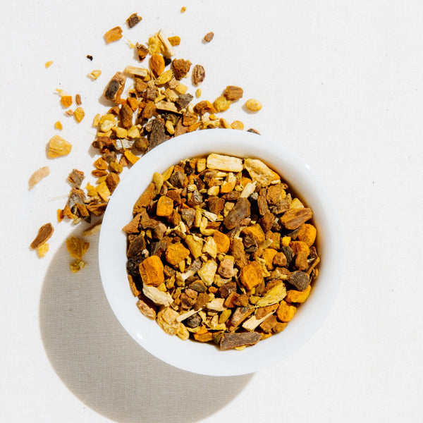 Bright Eyed loose leaf herbal blend with turmeric, ginger, and cinnamon in a white bowl on a light background