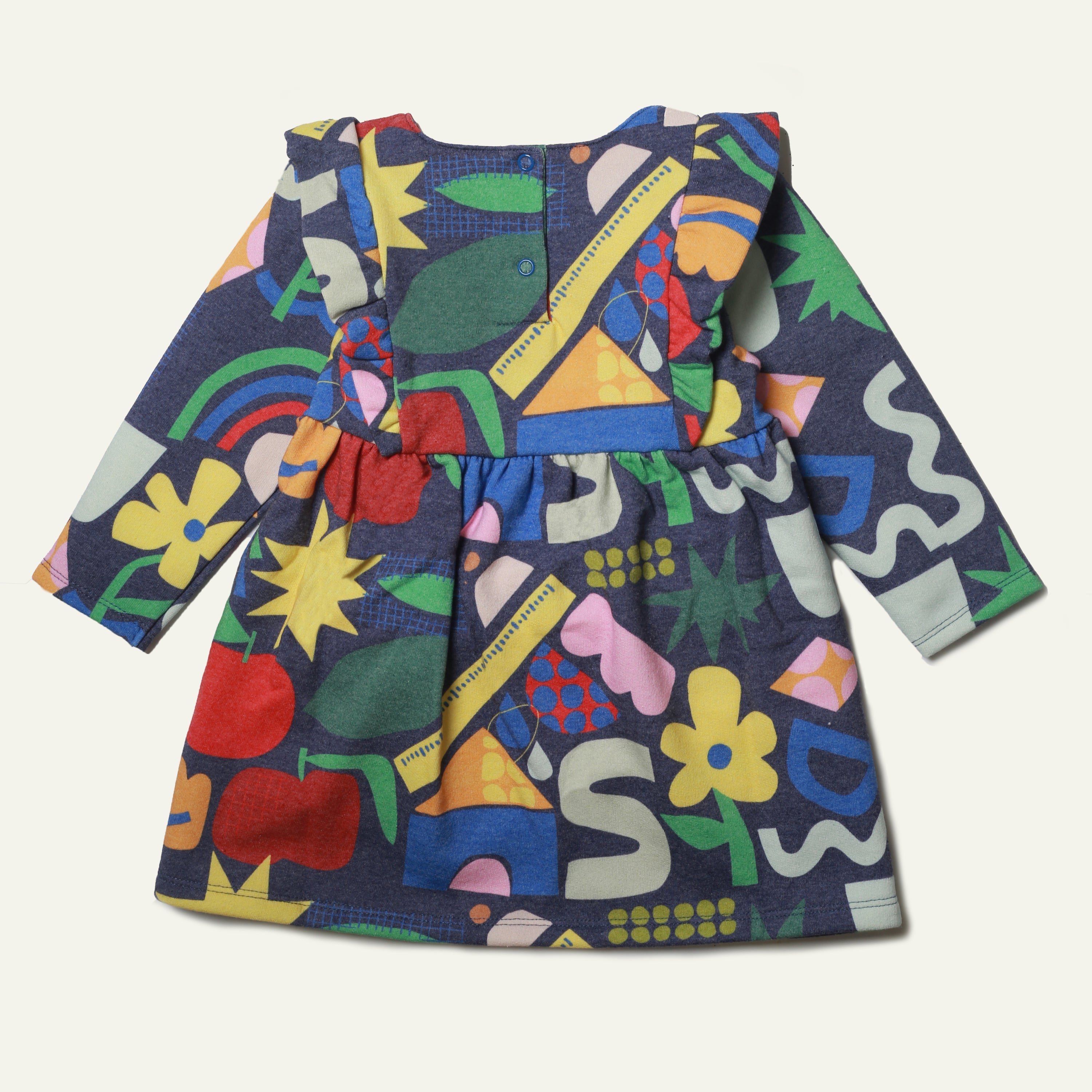 Close-up detail of the Mon Coeur baby ruffle dress showing the multicolour non-toxic print and snap button back fastening