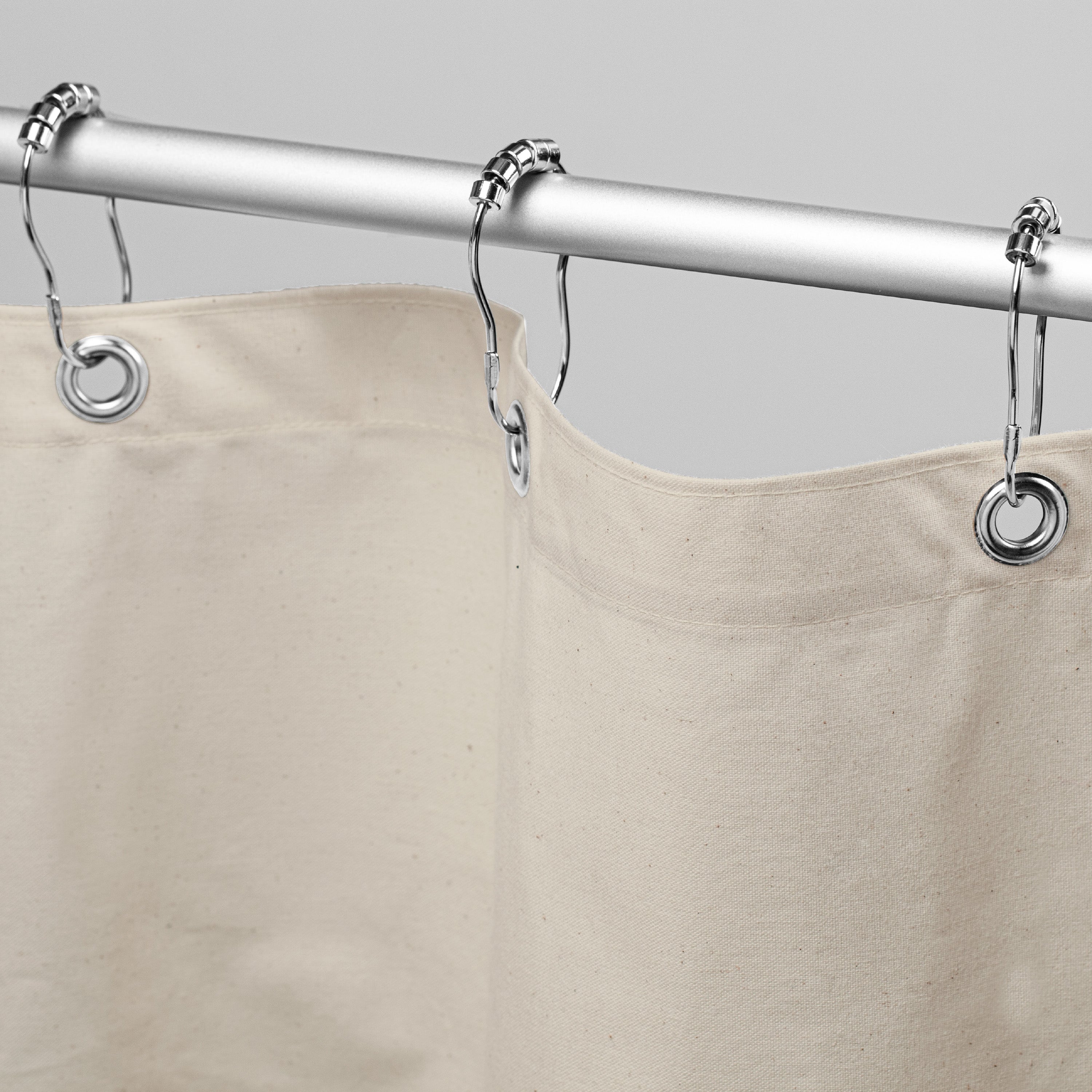 Beige shower curtain with silver rings on a gray background