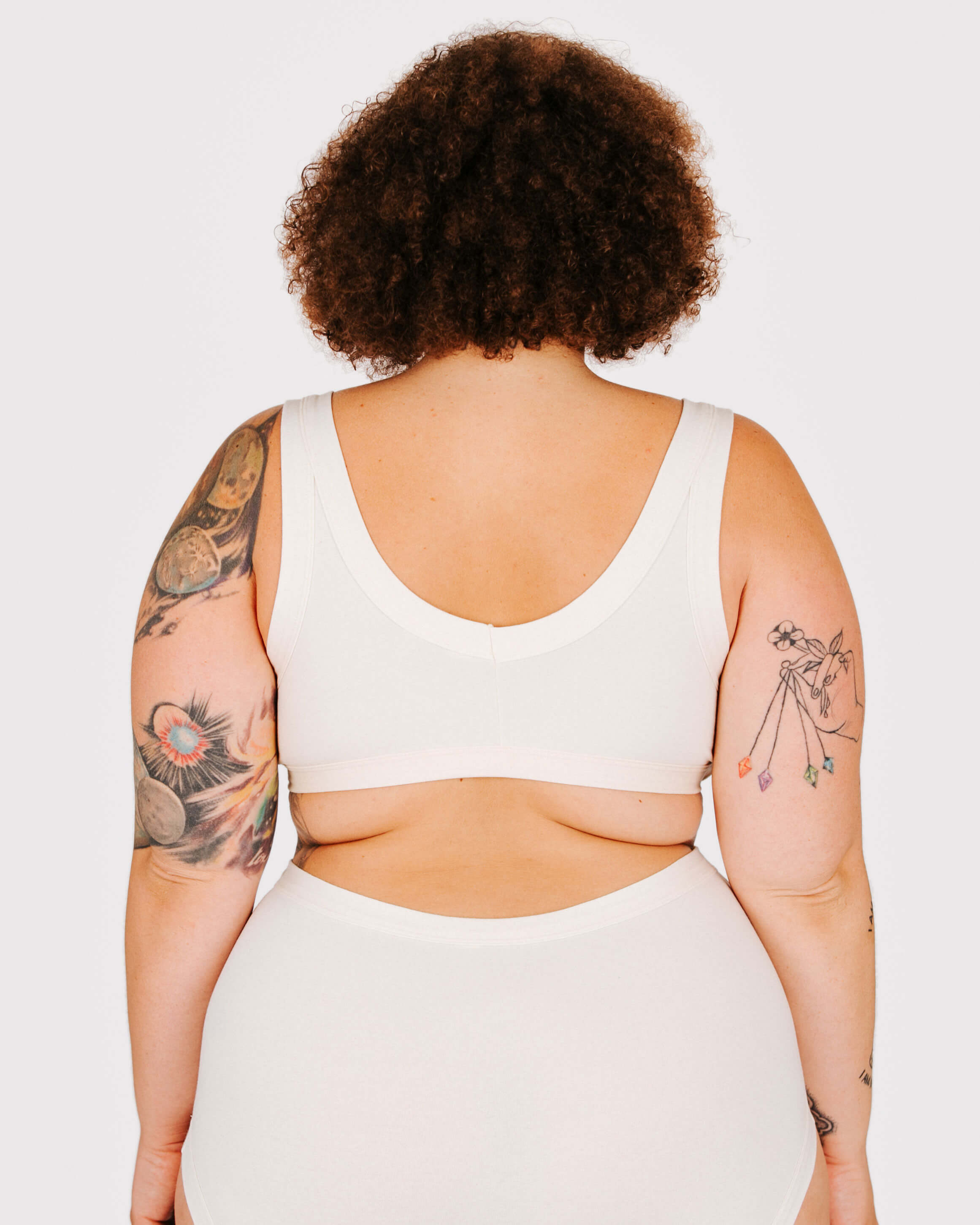 Person wearing a white sports bra and leggings set on a plain background