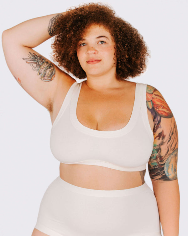 Person wearing a white sports bra and shorts on a plain background