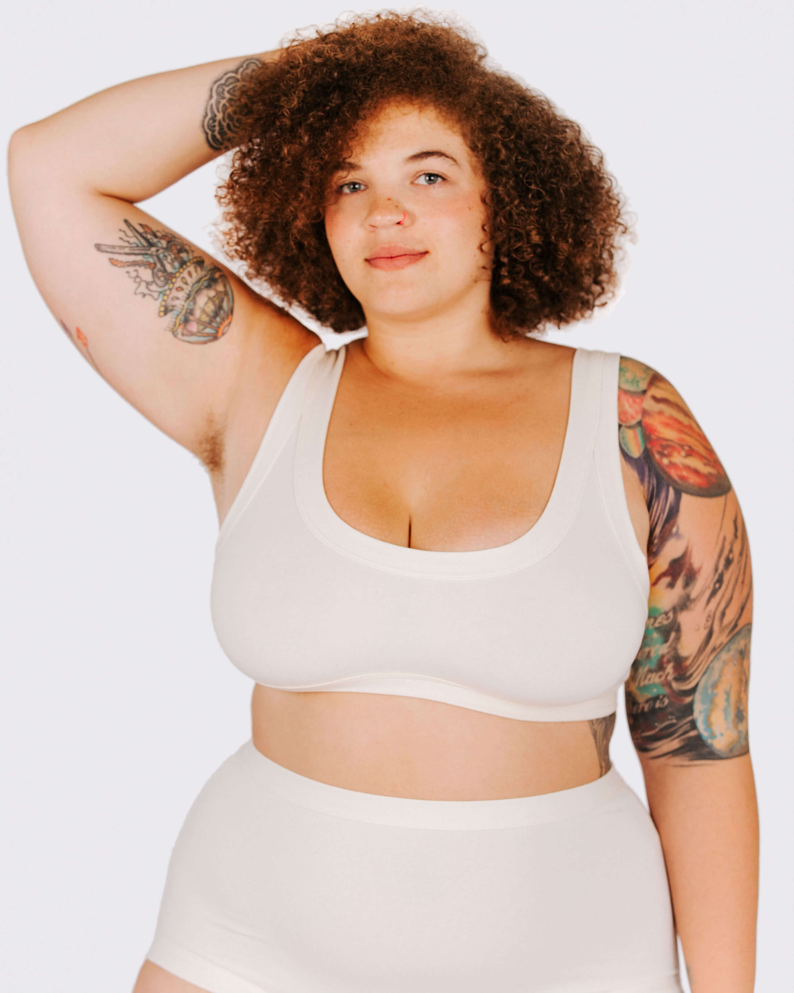 Person wearing a white sports bra and shorts on a plain background