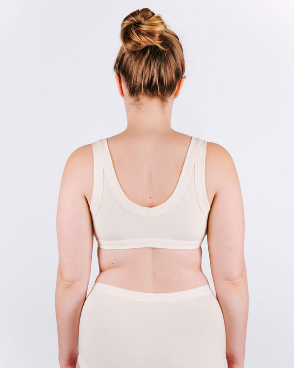 Woman wearing a white tank top against a plain background