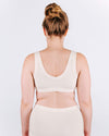 Woman wearing a white tank top against a plain background