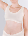 Person wearing a beige tank top against a plain background