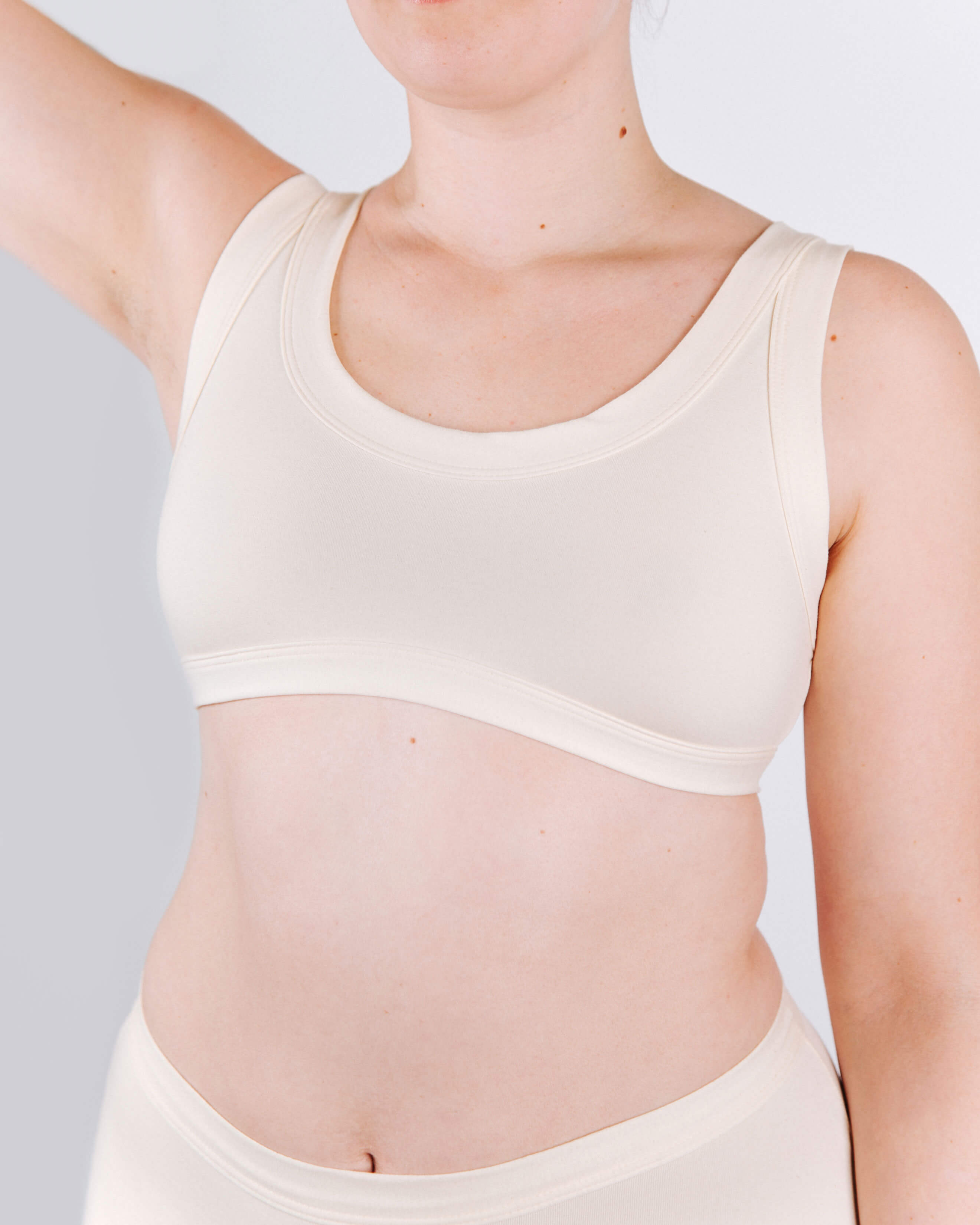 Person wearing a beige tank top against a plain background