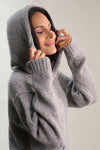 Woman wearing a gray hoodie against a plain background