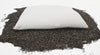 White pillow on a bed of black seeds or grains
