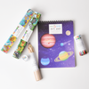 Children's art supplies including a notebook with space-themed design, colored pencils, and markers on a white background.