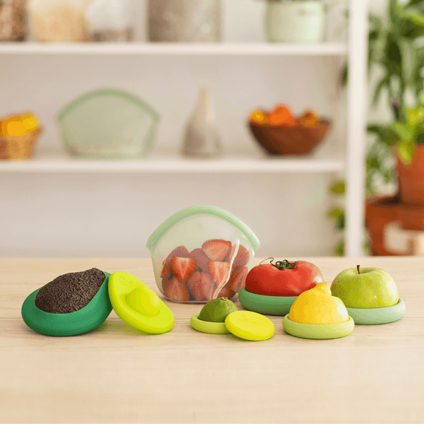 Colorful silicone food covers on a kitchen counter with a fruit container in the background.
