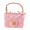 Pink handbag with gold handle and bow on a white background
