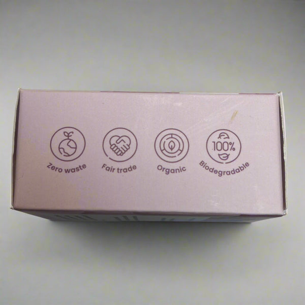 Small rectangular box with icons on a reflective surface: organic, Fair trade, ero waste and biodegradable shampoo bar. 