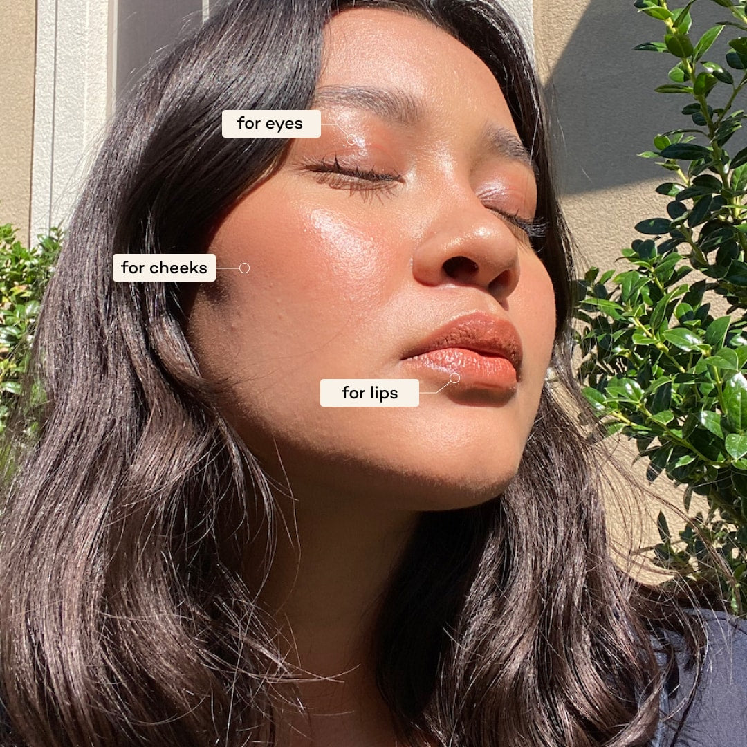 Woman applying makeup to her face with labels for eyes, cheeks, and lips.