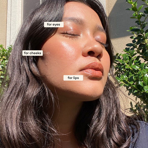 Woman applying makeup to her face with labels for eyes, cheeks, and lips.