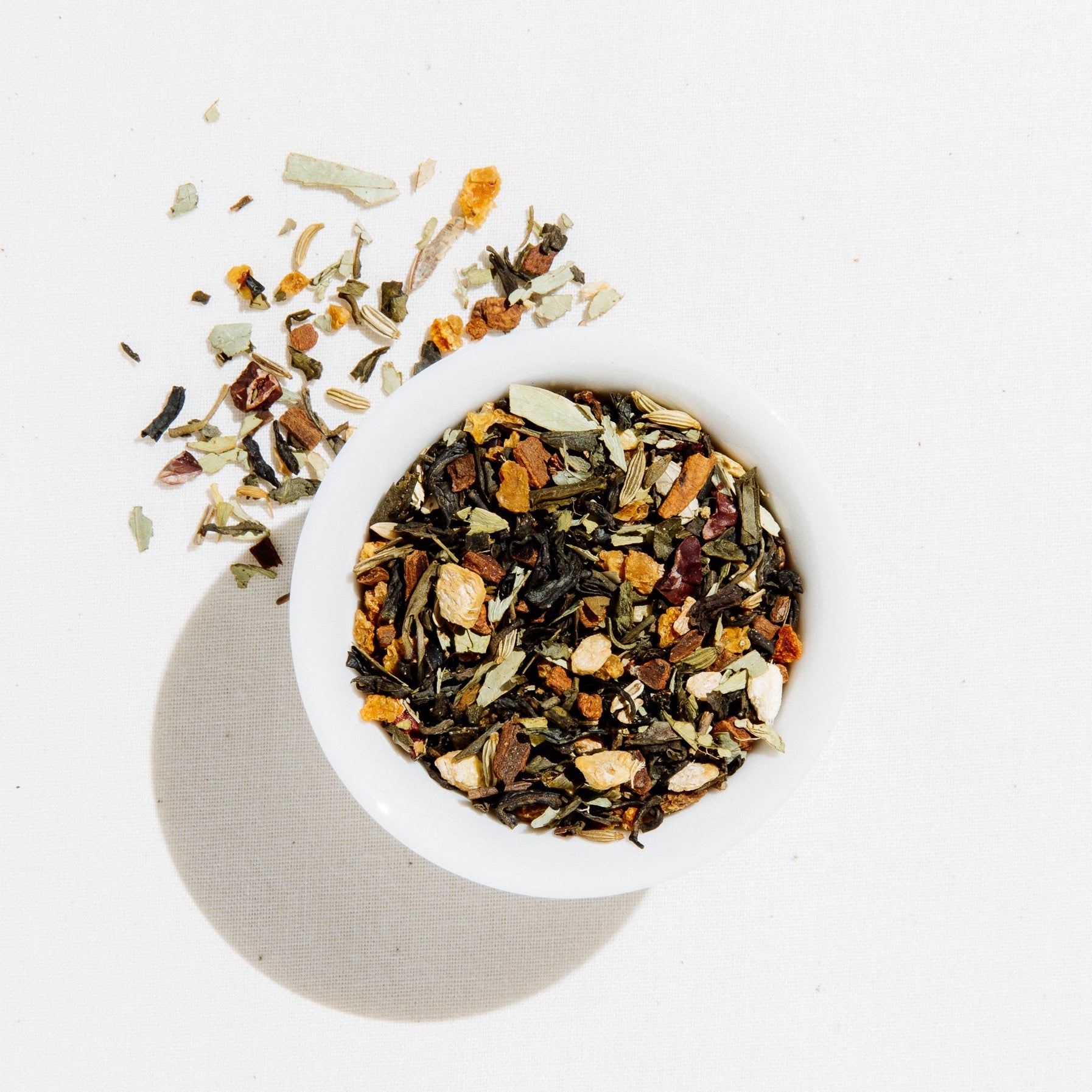 White bowl filled with a mix of dried herbs and spices on a light background